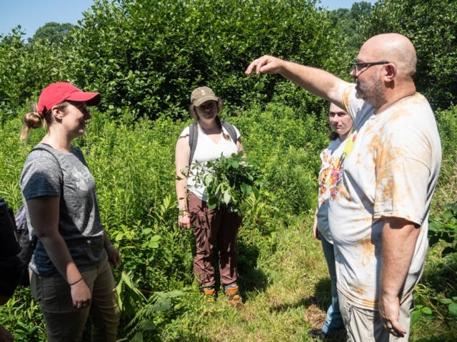A group discussing plant stems and leaves during a woody plant identification workshop.