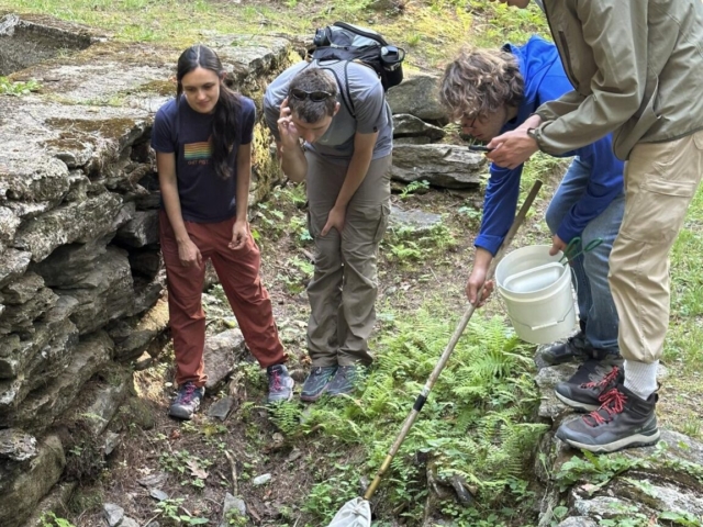 Attendees using a dip net to collect aquatic organisms at the Wachusett Bioblitz.